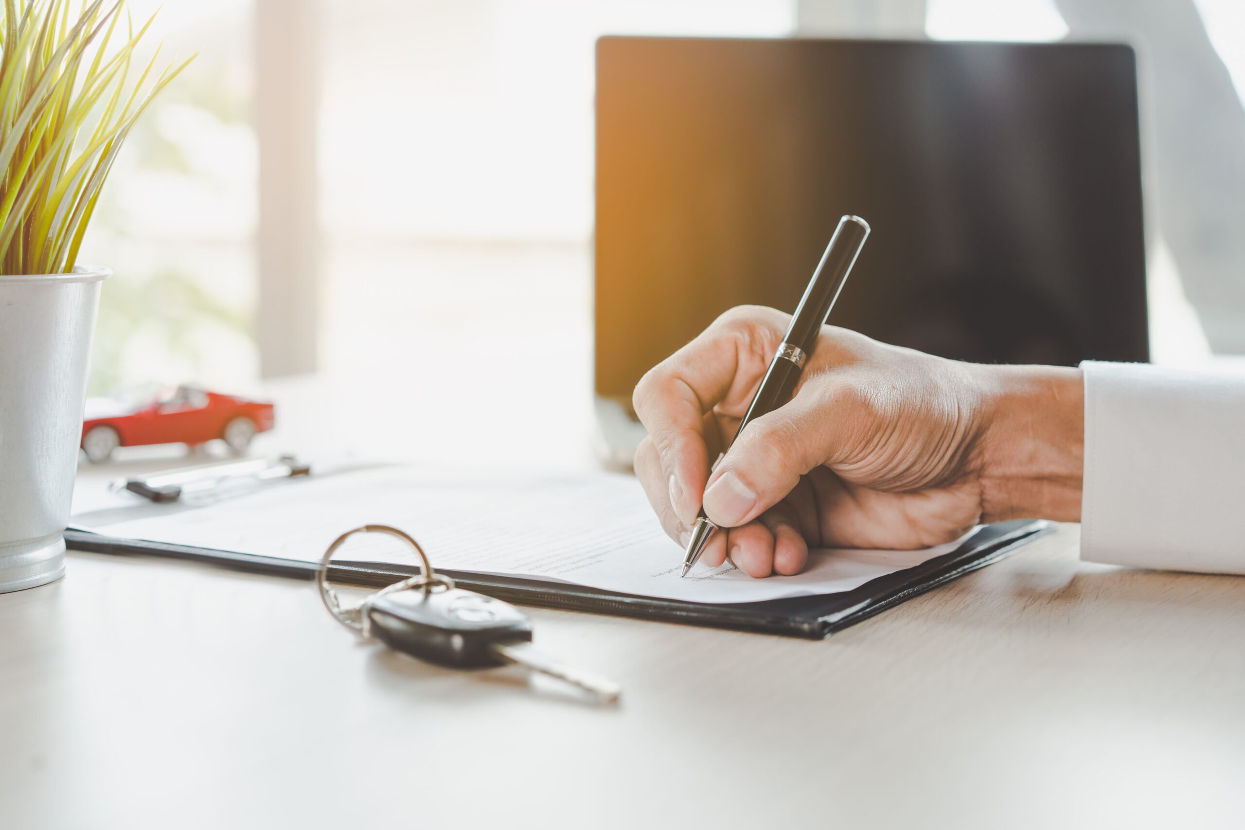 close up shots hands of client signing car asset finance form.