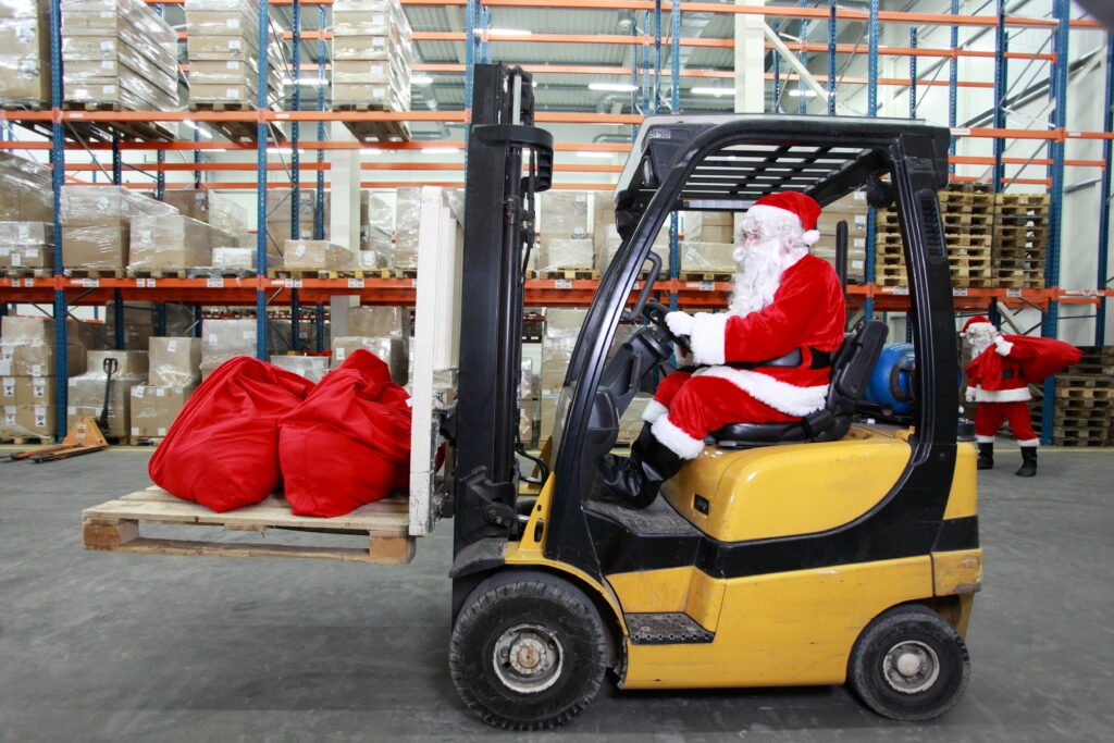 A person in a santa garment driving a forklift Description automatically generated with medium confidence