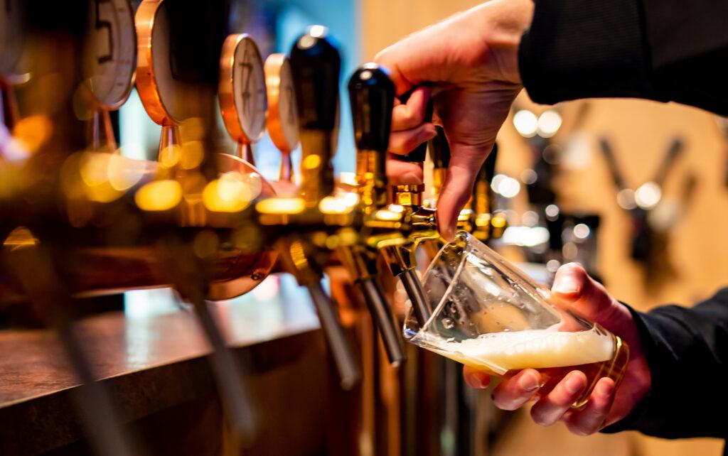 man pouring pint in brewery to glass